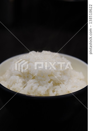 Freshly Cooked Steamed White Rice in a Black Bowl on Dark Background, Korean Traditional Staple Food, High Quality Macro Shot Freshly Cooked Steamed White Rice in a Black Bowl on Dark Background, Korean Traditional Staple Food, High Quality Macro Shot 138518622
