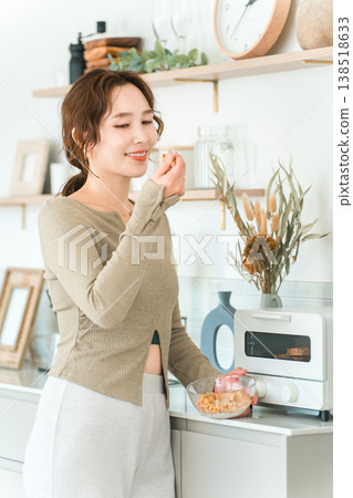 一位亞洲女性在廚房裡輕鬆地享用格蘭諾拉麥片早餐。 138518633