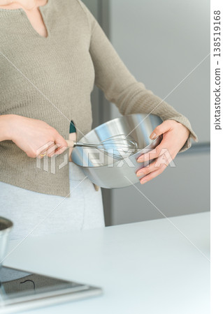 一位女士在廚房裡用碗和打蛋器做飯。 138519168