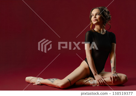 Tattooed Ballerina in a Black Leotard Sitting on a Red Background Tattooed Ballerina in a Black Leotard Sitting on a Red Background 138519377