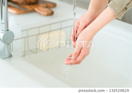 A woman's hands as she washes them in the kitchen sink (water-related work, rough hands). A woman's hands as she washes them in the kitchen sink (water-related work, rough hands). 138520629