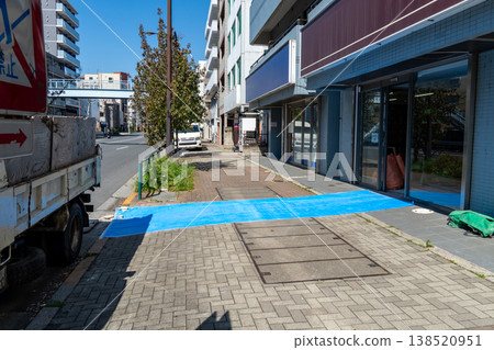 Blue tarpaulins laid out to protect the sidewalk. 138520951