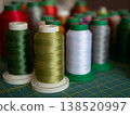 Colorful spools of sewing and embroidery thread arranged on a cutting mat. The vibrant threads showcase a variety of textures and hues for creative textile projects 138520997