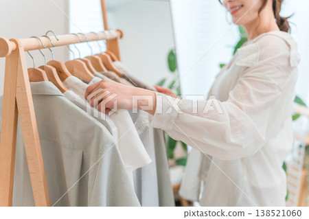 一位亞洲女性正在從衣架上挑選衣服(試穿衣服、搭配衣服、穿衣服、準備出門)。 一位亞洲女性正在從衣架上挑選衣服(試穿衣服、搭配衣服、穿衣服、準備出門)。 138521060
