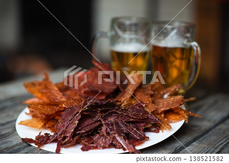 Snacks for beer on a plate on a wooden background. 2 blurry glasses of beer in the background 138521582
