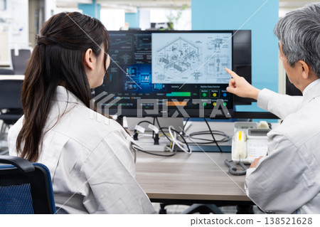 A man and a woman in work clothes are having a meeting while looking at a computer screen. A man and a woman in work clothes are having a meeting while looking at a computer screen. 138521628