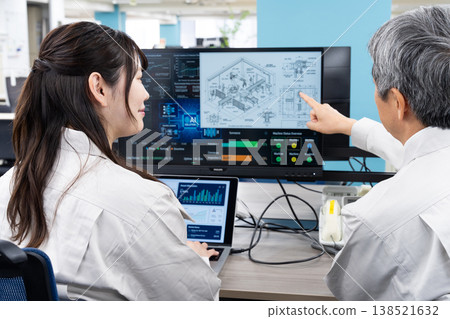 A man and a woman in work clothes are having a meeting while looking at a computer screen. A man and a woman in work clothes are having a meeting while looking at a computer screen. 138521632