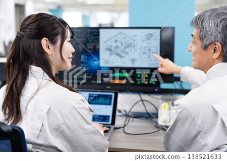 A man and a woman in work clothes are having a meeting while looking at a computer screen. A man and a woman in work clothes are having a meeting while looking at a computer screen. 138521633