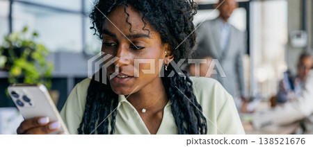 Female professional examines timesensitive message on mobile device Female professional examines timesensitive message on mobile device 138521676