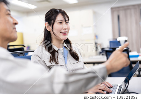 A man and a woman in work clothes are having a meeting while looking at a computer screen. A man and a woman in work clothes are having a meeting while looking at a computer screen. 138521852