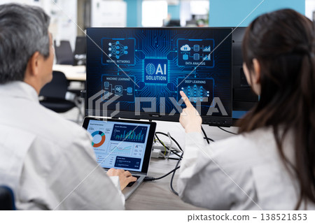A man and a woman in work clothes are having a meeting while looking at a computer screen. A man and a woman in work clothes are having a meeting while looking at a computer screen. 138521853