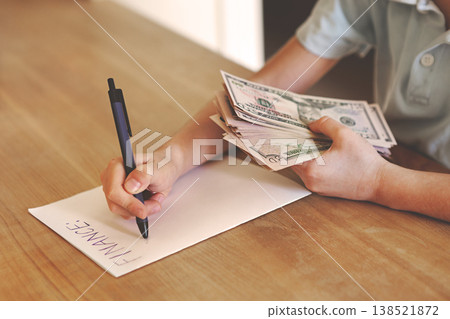 Child counting dollar bills over finance notes on wooden desk, young kid learning to manage money and savings, financial literacy education concept indoors, close up Hands with money Child counting dollar bills over finance notes on wooden desk, young kid learning to manage money and savings, financial literacy education concept indoors, close up Hands with money 138521872