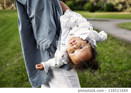 Playful little toddler girl hanging upside down in mother arms during summer walk in green park, joyful kid, fun moment, authentic family lifestyle outdoors in nature. Mom with child Playful little toddler girl hanging upside down in mother arms during summer walk in green park, joyful kid, fun moment, authentic family lifestyle outdoors in nature. Mom with child 138521884