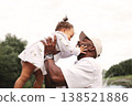 Smiling African American father gently embracing toddler daughter against sky outdoors, loving hug, portrait with copy space. Happy dad with little child 138521886