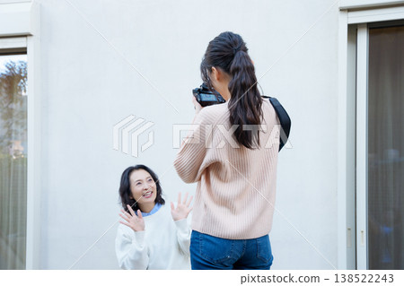 A portrait of a close mother and daughter taking a picture of the mother on the veranda. 138522243