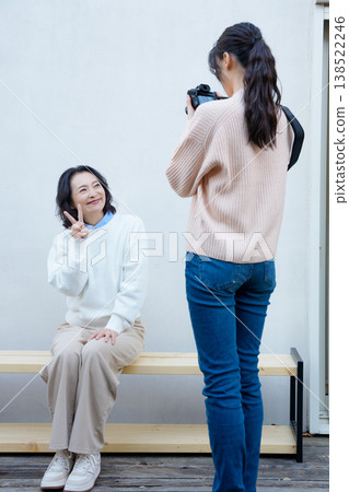 A portrait of a close mother and daughter taking a picture of the mother on the veranda. A portrait of a close mother and daughter taking a picture of the mother on the veranda. 138522246