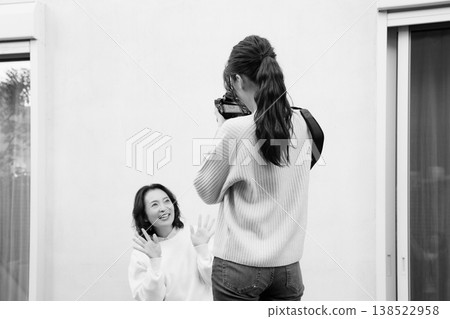 A close mother-daughter portrait taken on a monochrome veranda. 138522958