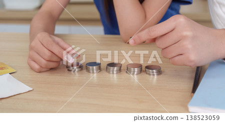 Hands arranging coins on a wooden table Hands arranging coins on a wooden table 138523059