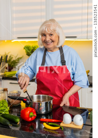 Senior old woman cooking homemade soup in kitchen tasting seasoning for healthy diet family dinner Senior old woman cooking homemade soup in kitchen tasting seasoning for healthy diet family dinner 138523541