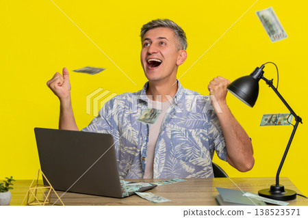 Adult man celebrating jackpot lottery win at laptop, falling cash money happy excited smiling face Adult man celebrating jackpot lottery win at laptop, falling cash money happy excited smiling face 138523571