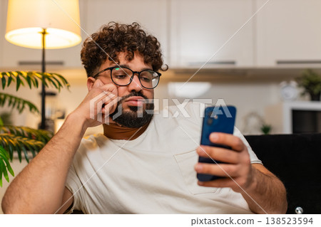 Arabian man bored scrolling smartphone news tired stressed demotivated looks drained evening indoors 138523594
