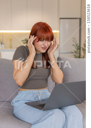Young woman with laptop rubs temples headache pause closes eyes tired takes break for relief needed Young woman with laptop rubs temples headache pause closes eyes tired takes break for relief needed 138523616