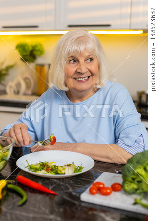 Senior old woman eating healthy salad in home kitchen thinking about diet plan choice and nutrition Senior old woman eating healthy salad in home kitchen thinking about diet plan choice and nutrition 138523632