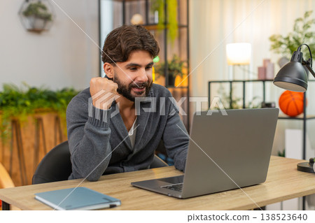Indian happy man submits project on laptop hits submit smiles fist pump celebrates victory good news Indian happy man submits project on laptop hits submit smiles fist pump celebrates victory good news 138523640