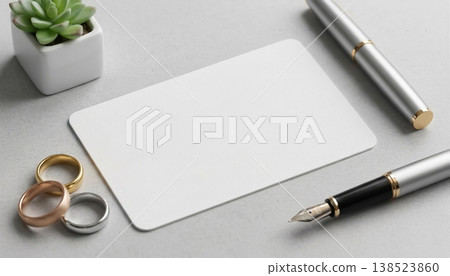 Writing tools and rings on a desk near a small plant with a blank card and a pen in a simple workspace setting Writing tools and rings on a desk near a small plant with a blank card and a pen in a simple workspace setting 138523860