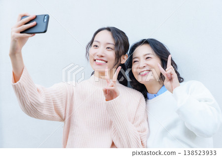 一幅母女親密合影，她們在陽台上用智慧型手機自拍。 138523933