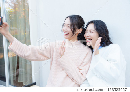 一幅母女親密合影,她們在陽台上用智慧型手機自拍。 一幅母女親密合影,她們在陽台上用智慧型手機自拍。 138523937