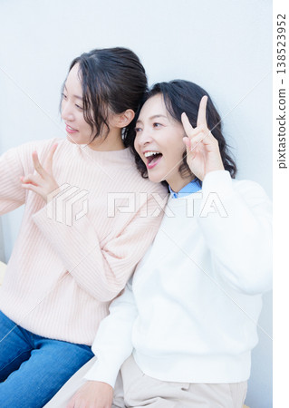 A portrait of a close mother and daughter taking a selfie on the veranda with their smartphones. A portrait of a close mother and daughter taking a selfie on the veranda with their smartphones. 138523952