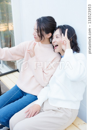 A portrait of a close mother and daughter taking a selfie on the veranda with their smartphones. A portrait of a close mother and daughter taking a selfie on the veranda with their smartphones. 138523953