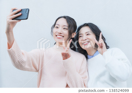 一幅母女親密合影，她們在復古風格的陽台上用智慧型手機自拍。 138524099