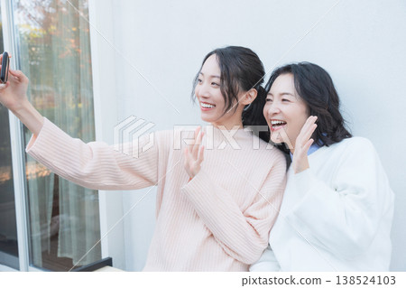 一幅母女親密合影,她們在復古風格的陽台上用智慧型手機自拍。 一幅母女親密合影,她們在復古風格的陽台上用智慧型手機自拍。 138524103