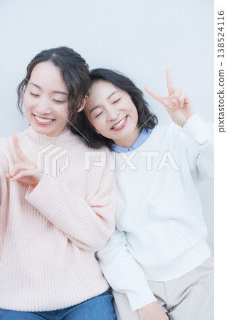 A portrait of a close mother and daughter taking a selfie with their smartphone on a retro-style veranda. A portrait of a close mother and daughter taking a selfie with their smartphone on a retro-style veranda. 138524116