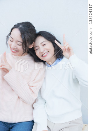 A portrait of a close mother and daughter taking a selfie with their smartphone on a retro-style veranda. A portrait of a close mother and daughter taking a selfie with their smartphone on a retro-style veranda. 138524117