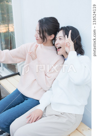 一幅母女親密合影,她們在復古風格的陽台上用智慧型手機自拍。 一幅母女親密合影,她們在復古風格的陽台上用智慧型手機自拍。 138524119