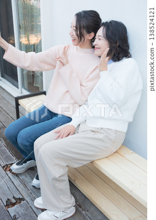 一幅母女親密合影,她們在復古風格的陽台上用智慧型手機自拍。 一幅母女親密合影,她們在復古風格的陽台上用智慧型手機自拍。 138524121