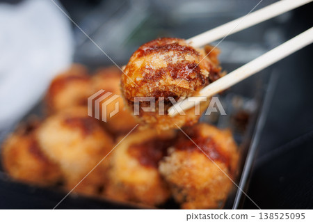 Fried takoyaki held with chopsticks Fried takoyaki held with chopsticks 138525095