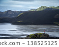 Hiker in the distance enjoying views on mountainous volcanic landscape with glacial river, Iceland 138525125