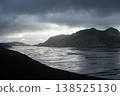 Sun setting behind mountains in glacial landscape with heavy storm clouds above, Iceland 138525130