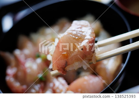 在一家與當地超市相連的小餐館裡，用筷子夾起一碗什錦醃魚中的一片醃魚。 138525393