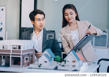 Real Estate Broker discussing with a customer model install solar roof house modern project in the office, real estate developer alternative energy, development business sustainable, zero energy, ESG. 138526320