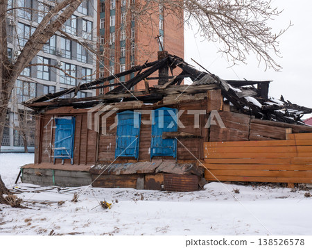 Old wooden house with shutters against modern high rise buildings covered in snow cold early spring urban contrast cityscape and winter atmosphere. 138526578