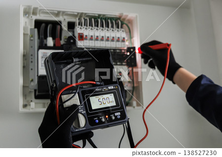 一名電工正在使用數位測試儀對配電盤進行絕緣電阻測量;安全檢查影像。 一名電工正在使用數位測試儀對配電盤進行絕緣電阻測量;安全檢查影像。 138527230