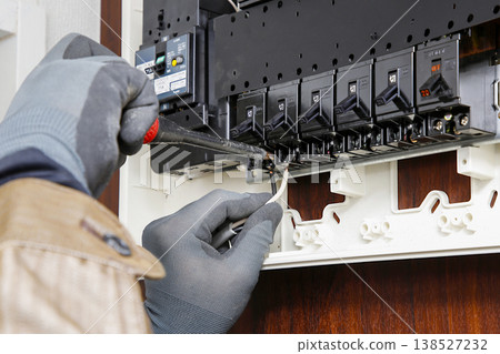 圖中一名電工正在工作，檢查配電盤並更換斷路器。 138527232