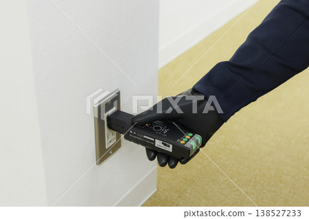 圖中一名電工正在檢查電源插座的運作。 138527233