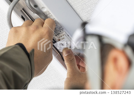 A scene of an electrician installing and wiring LED lighting. Ceiling lighting maintenance image. 138527243