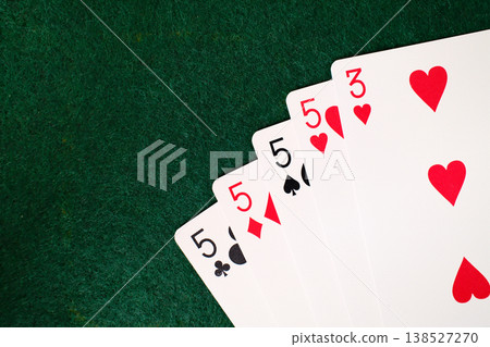 4 Of A Kind Combination Playing cards arranged on dark green felt casino gambling table closeup detail 4 Of A Kind Combination Playing cards arranged on dark green felt casino gambling table closeup detail 138527270